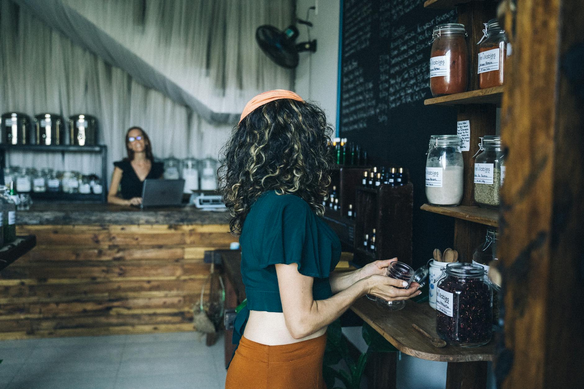 Kobieta wybiera ekologiczne warzywa w małym, bezplastikowym sklepie
