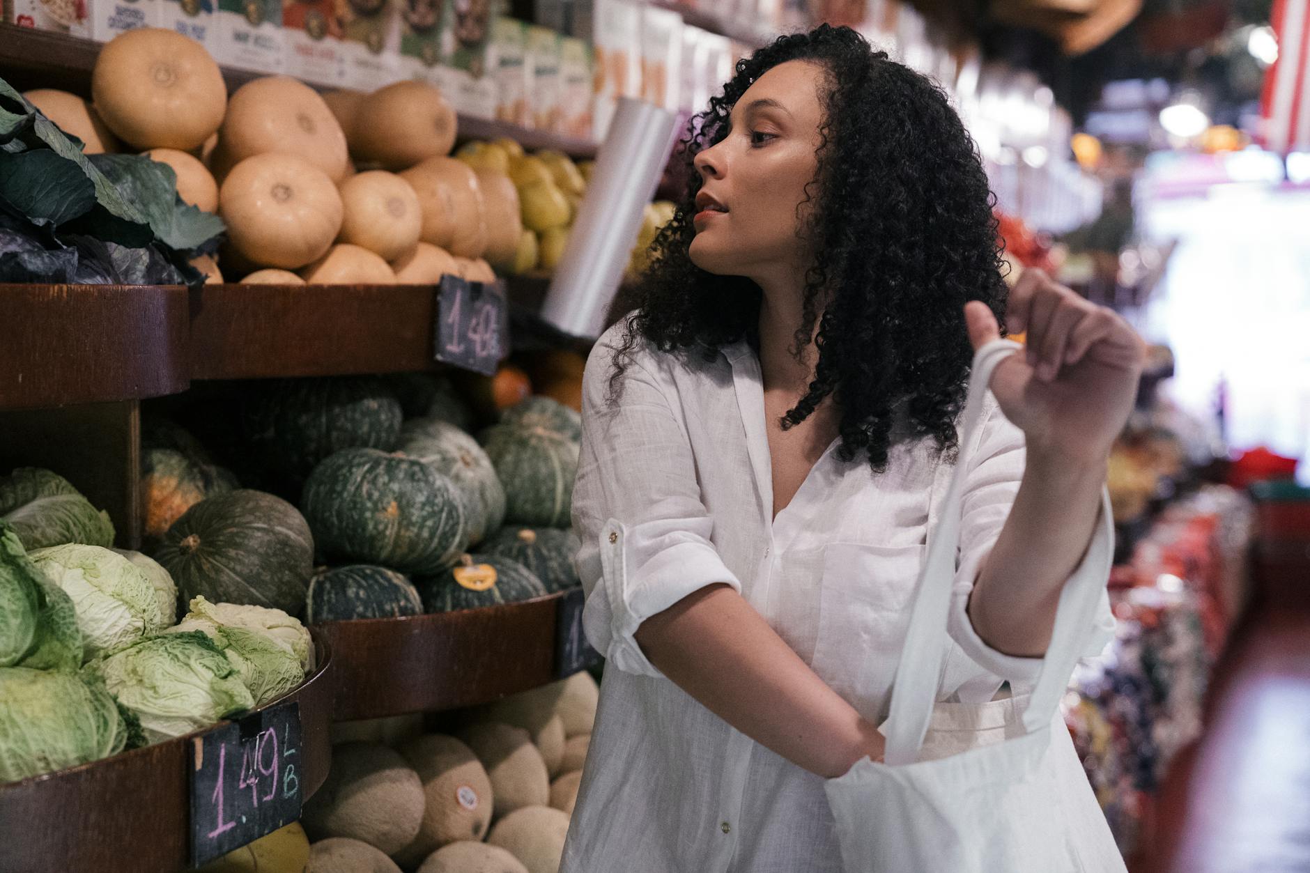 Kobieta z ekotorbą wybiera warzywa na lokalnym targu bez plastiku