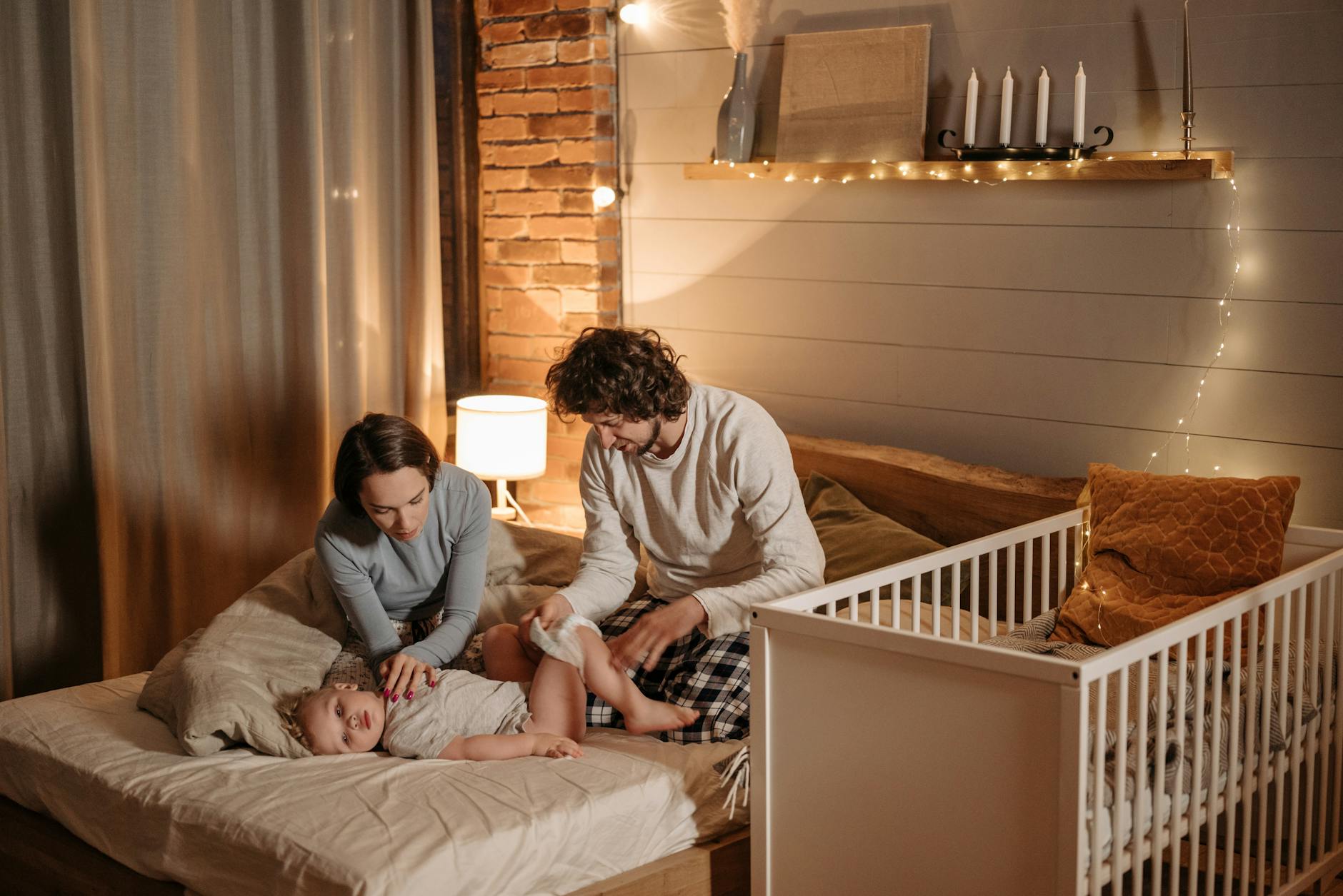 Akcja „Wymień żarówkę”: edukacja o energii w praktyce dla rodzin Rodzice przewijają malucha w przytulnym, ciepło oświetlonym pokoju