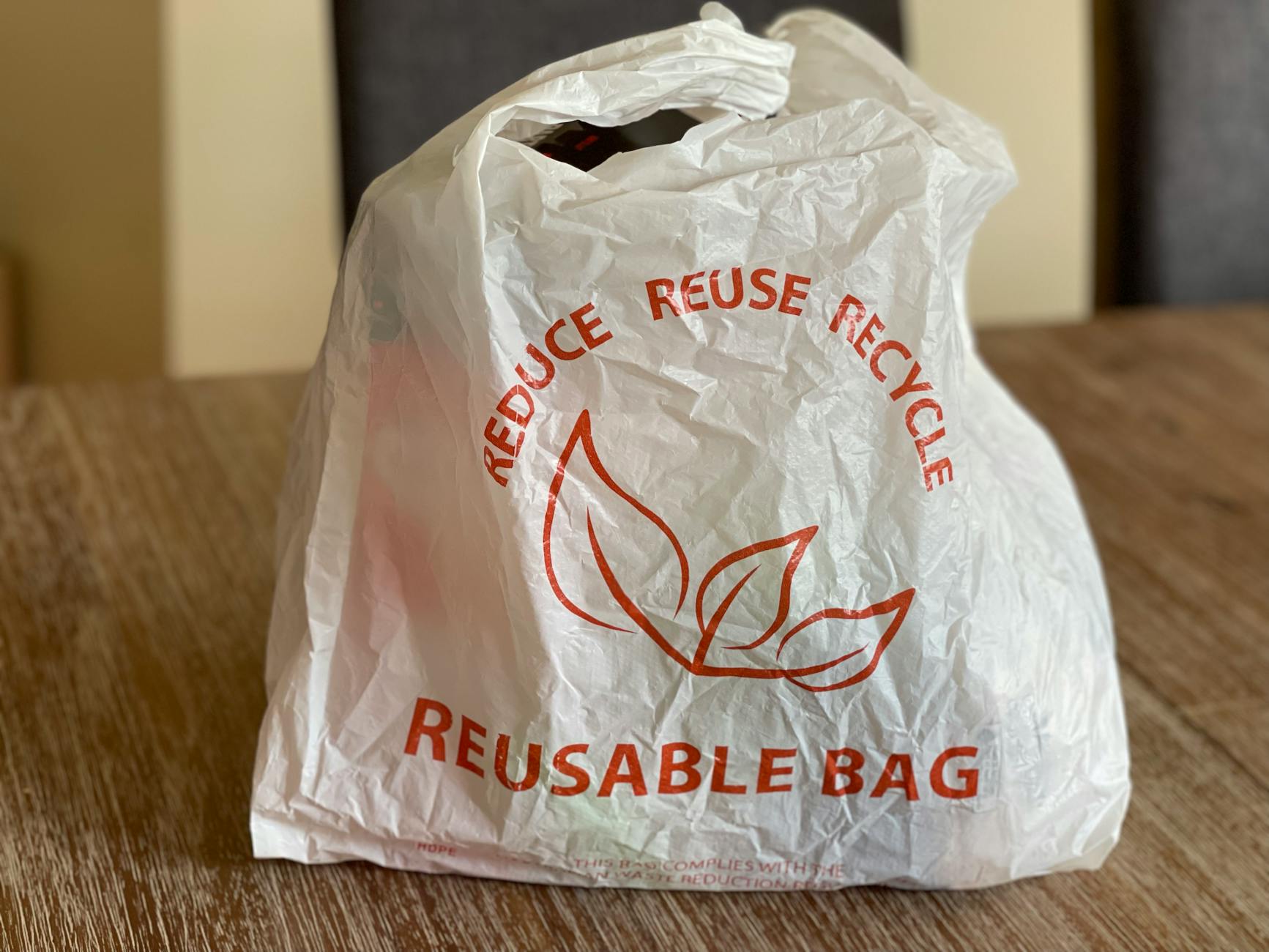 Płócienna torba wielokrotnego użytku reduce reuse recycle na drewnianym stole