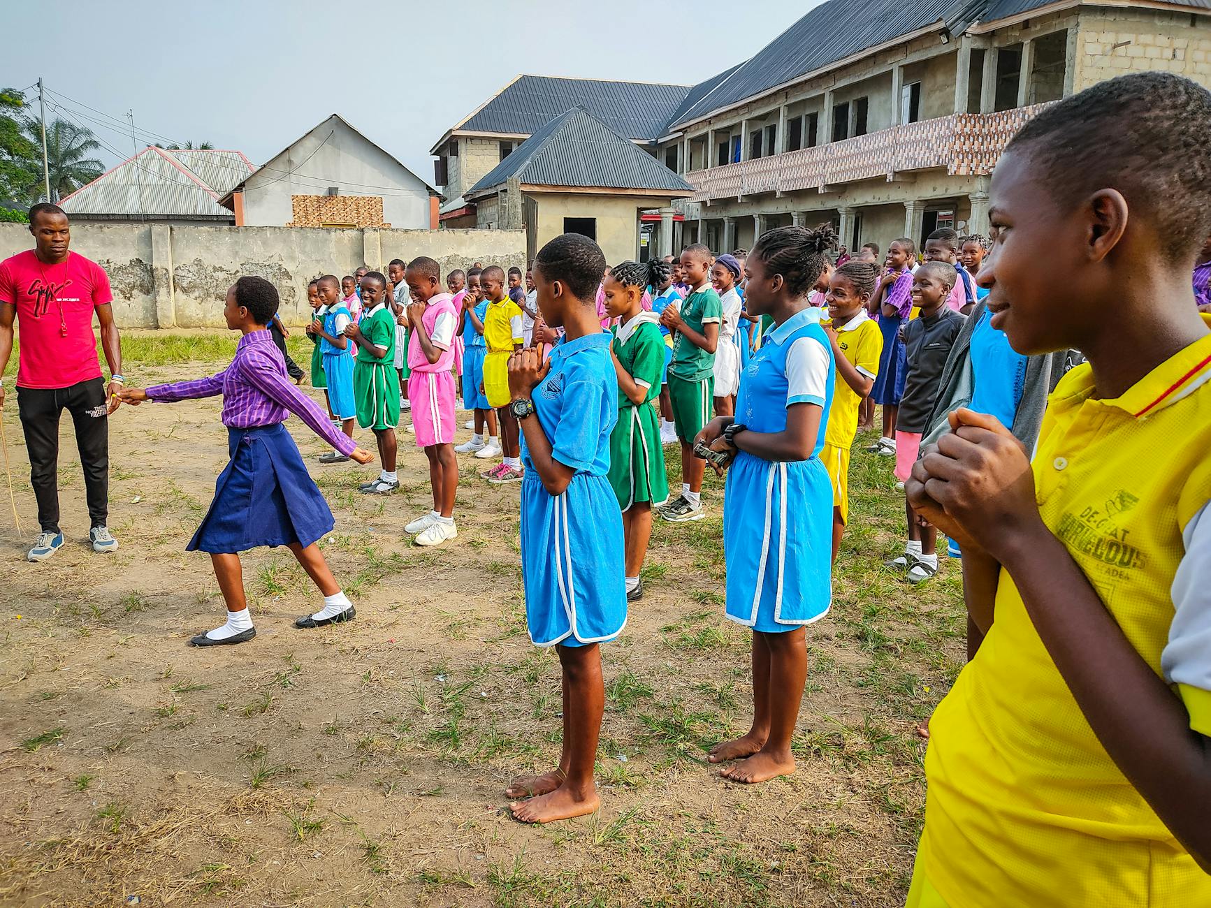 Uczniowie w szkolnych mundurkach biorą udział w zajęciach na podwórku