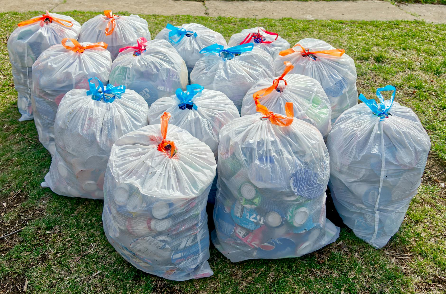 Worki z plastikowymi odpadami na trawie podczas zbiórki recyklingu