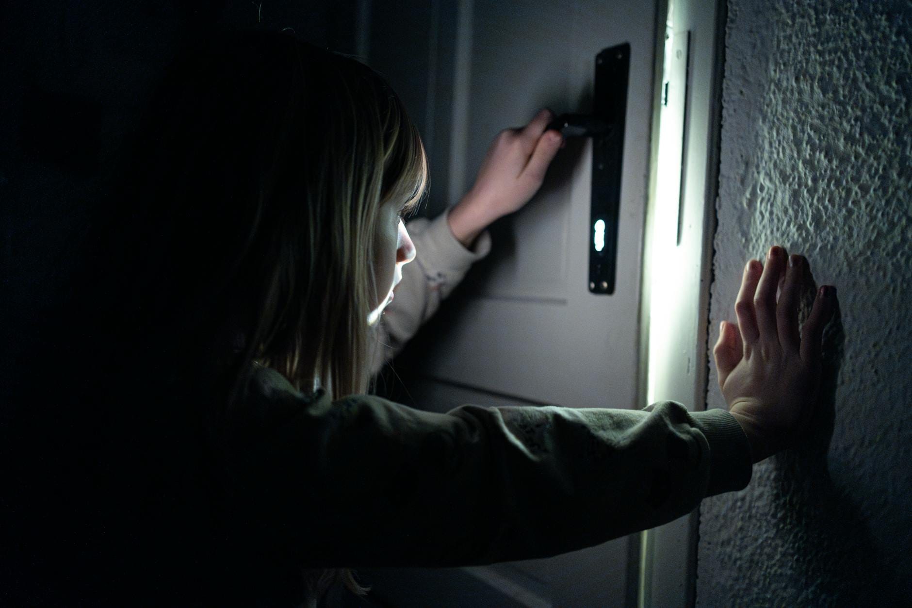 Dziecko otwierające drzwi w przygaszonym świetle w mieszkaniu