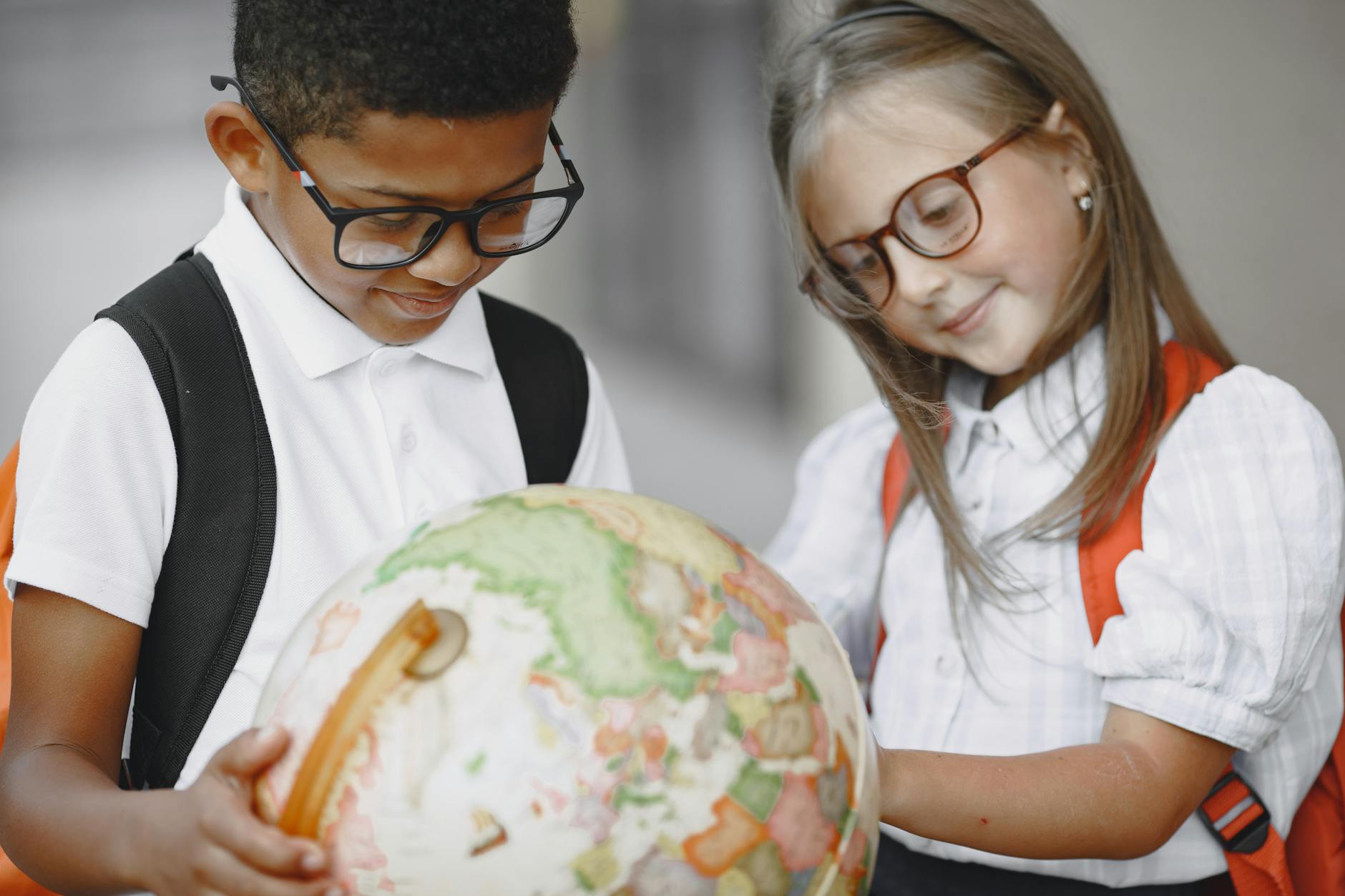 Dziewczynka i chłopiec oglądają globus podczas wspólnej nauki