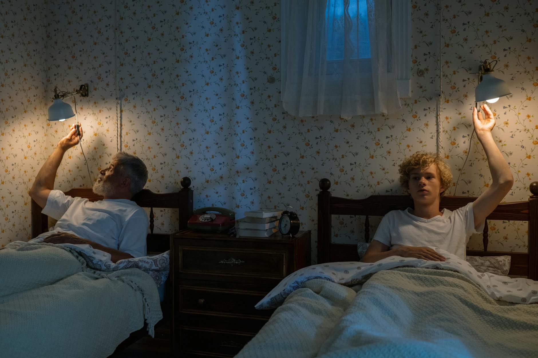 Starszy i młodszy mężczyzna gaszą lampki nocne w przytulnej sypialni