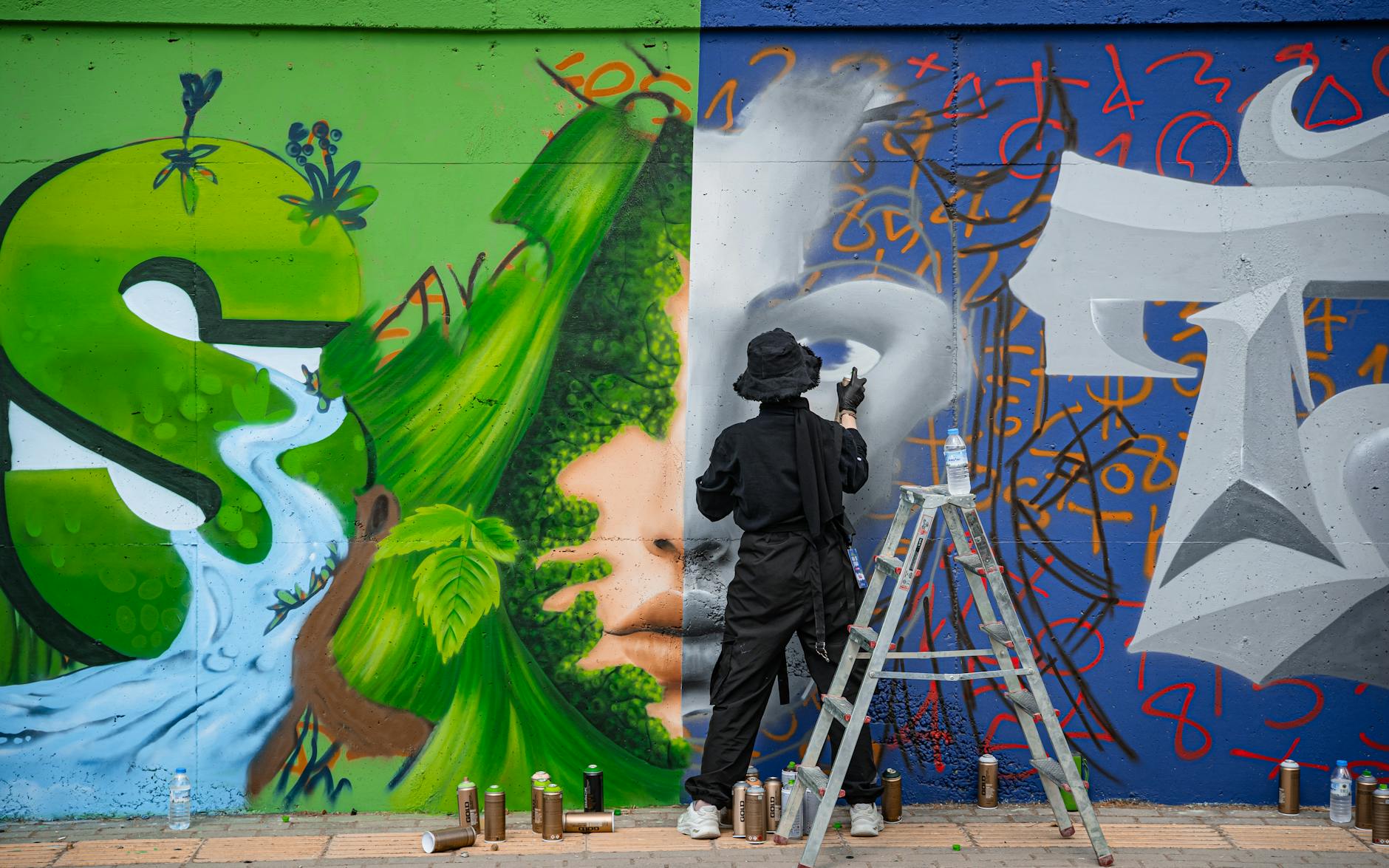Artysta maluje barwny mural z motywami natury na miejskiej ścianie