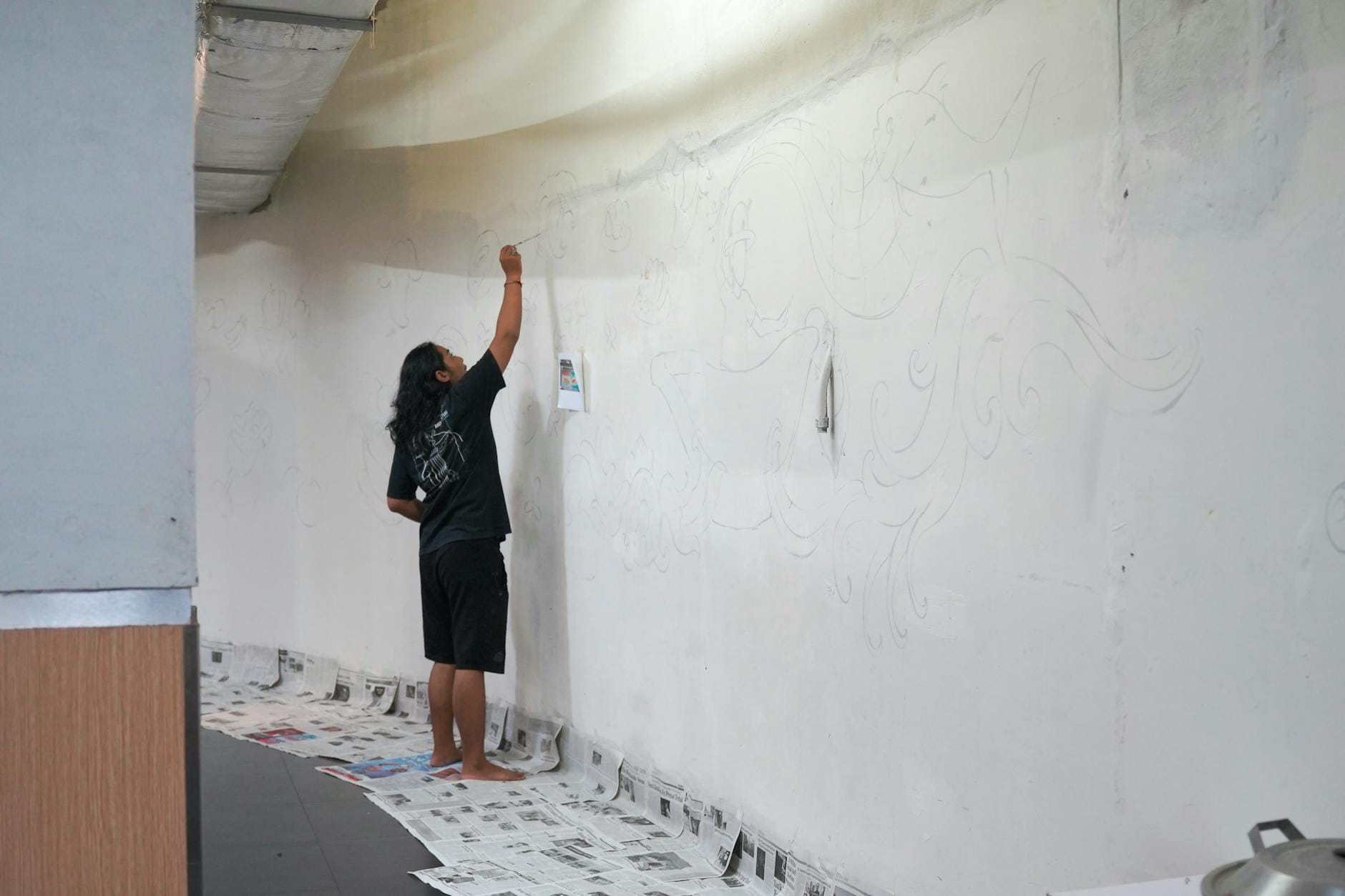 Artysta szkicuje kolorowy mural na ścianie w przestrzeni miejskiej