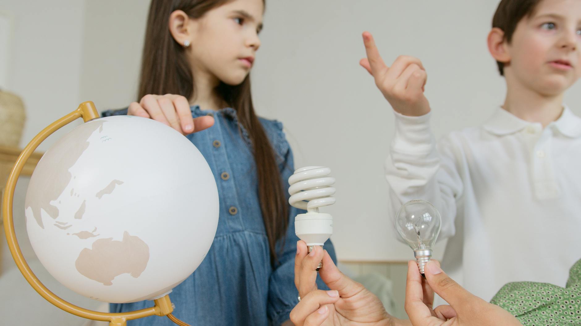 Dzieci uczą się o odnawialnych źródłach energii przy globusie i żarówkach