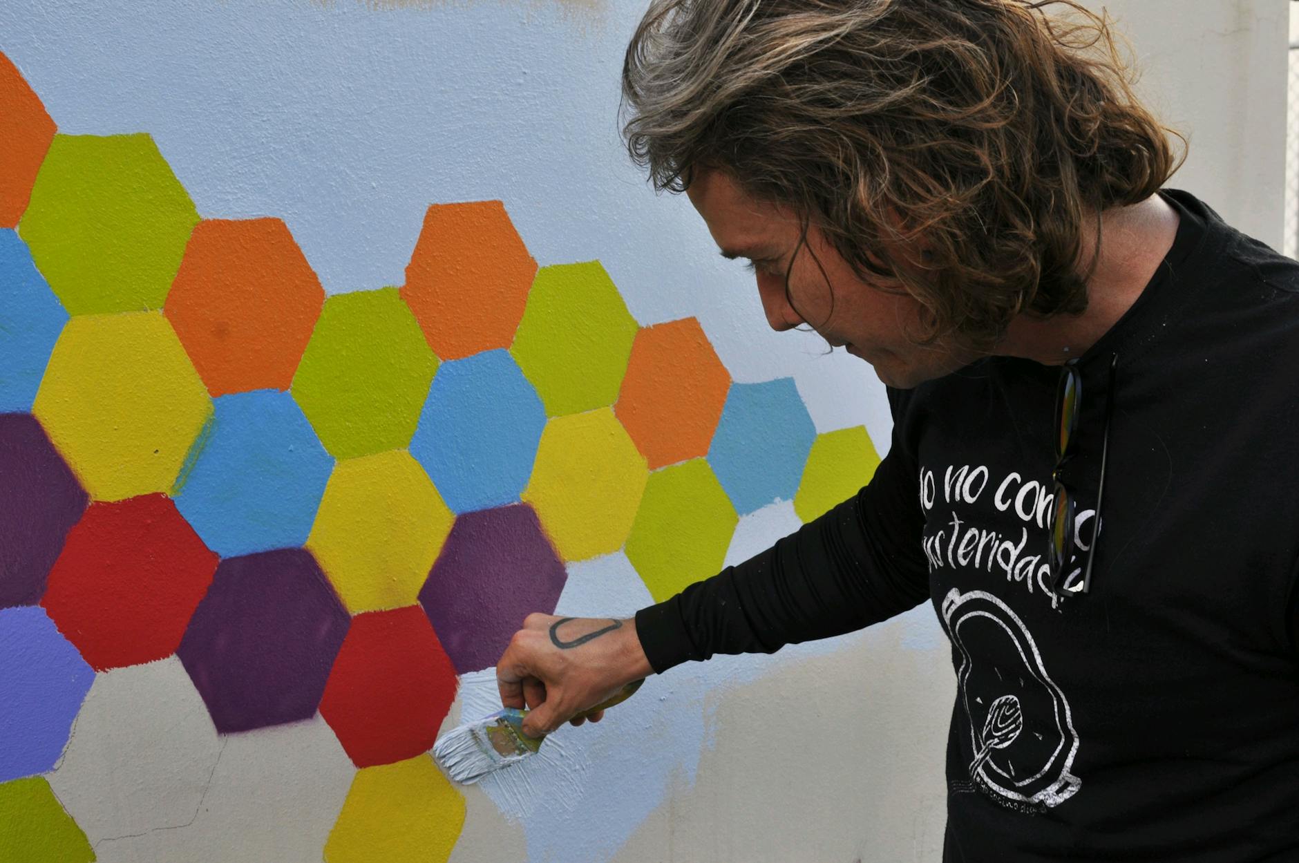 Mężczyzna maluje kolorowy, geometryczny mural na miejskiej ścianie