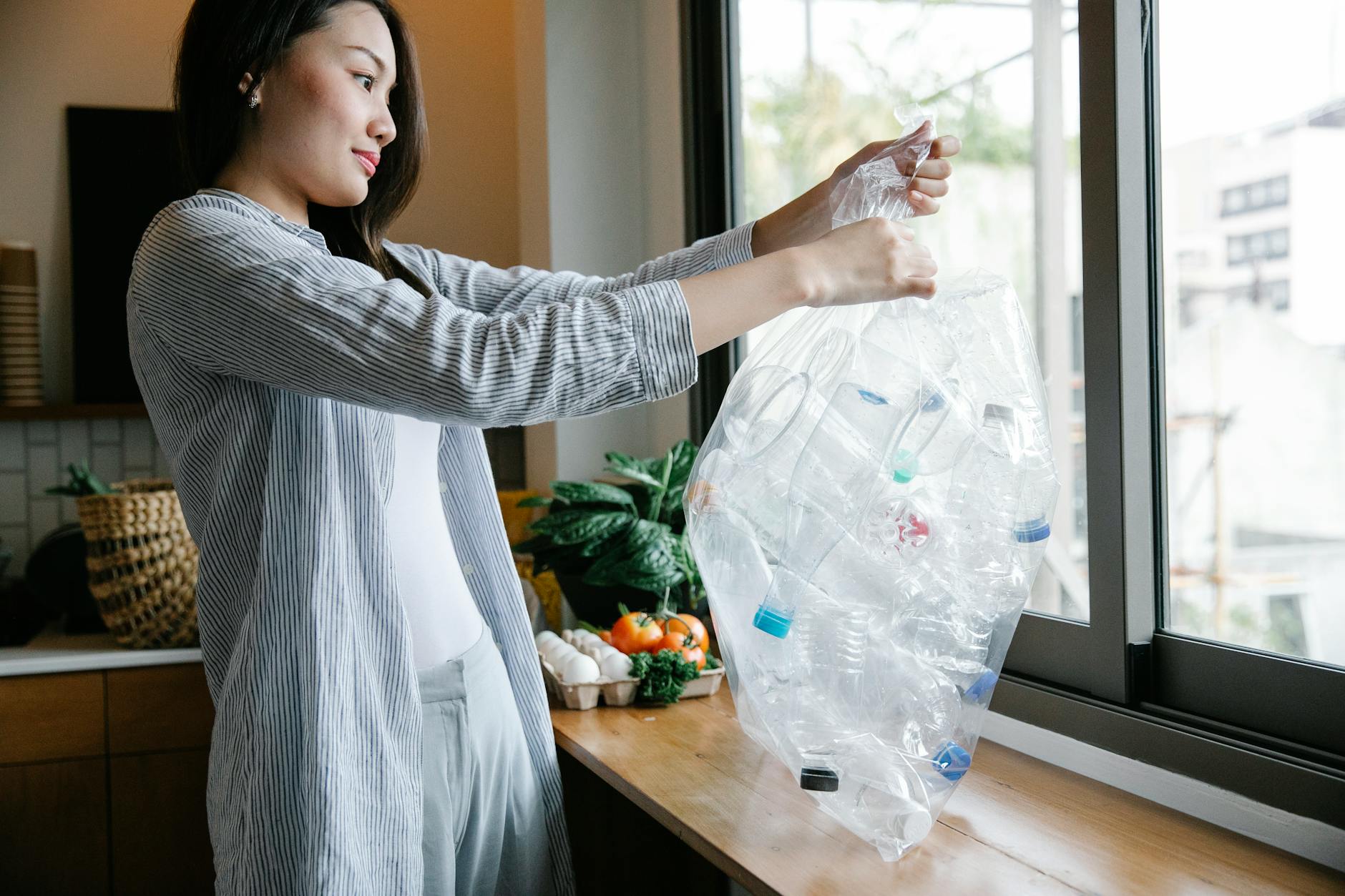 Kobieta w kuchni trzyma przezroczystą torbę z plastikowymi butelkami