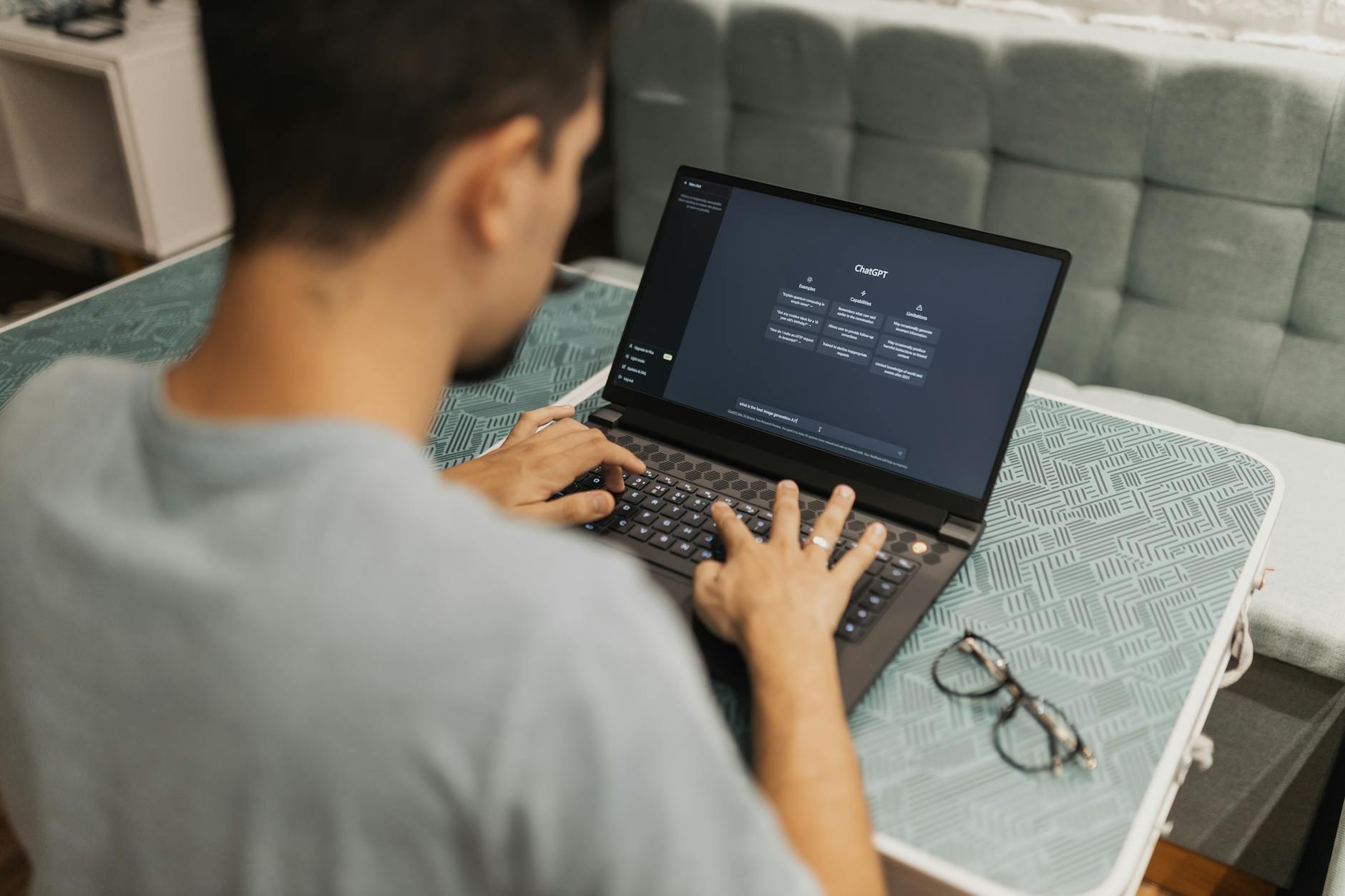 Mężczyzna pracujący przy laptopie z otwartym interfejsem ChatGPT
